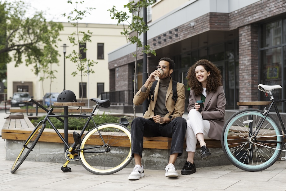 Two friends drinking takeaway coffee with city bikes 